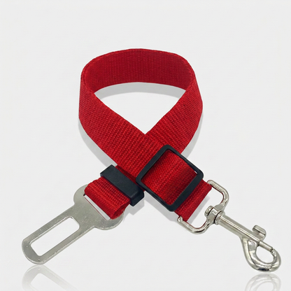 Red nylon dog car seat belt tether with a metal seat belt buckle clip, adjustable slider and swivel snap hook on a white background.