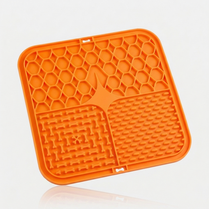Orange silicone lick mat for dogs with three textured feeding zones, shown at an angle on a white background.