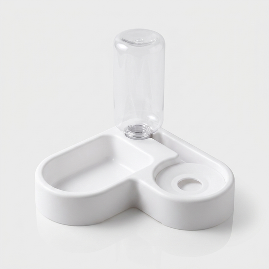 A white double bowl feeder holds dry kibble on one side and fresh water in the other.