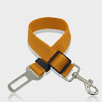 Mustard yellow nylon dog car seat belt tether with a metal seat belt buckle clip, adjustable slider and swivel snap hook on a white background.